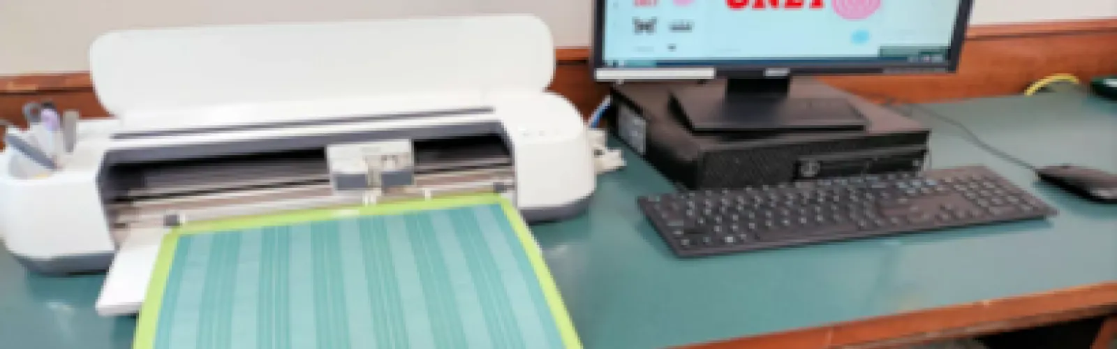 Cricut machine next to a computer monitor